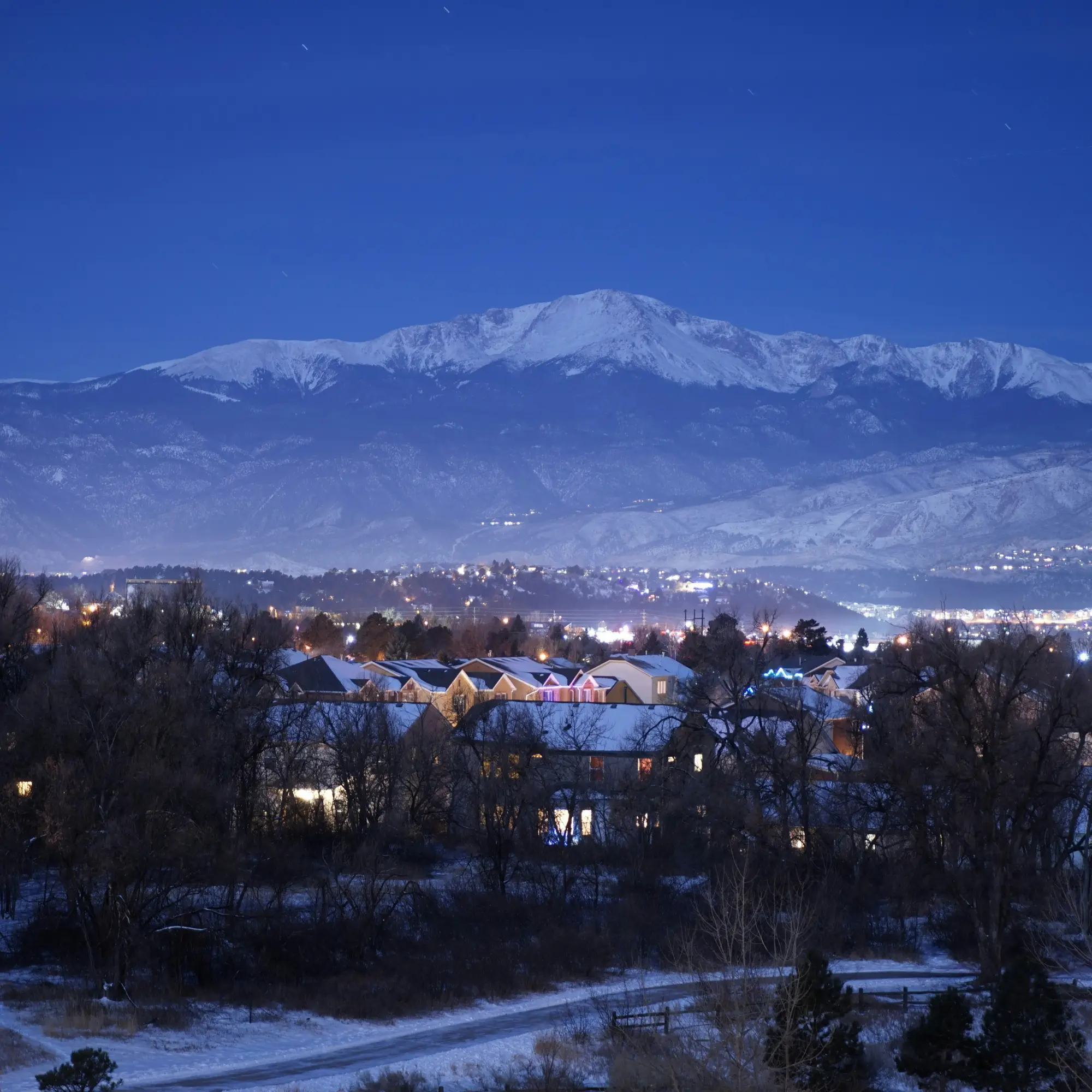 Colorado Springs neighborhood in Winter with snowy rooftops and Pikes Peak in the background